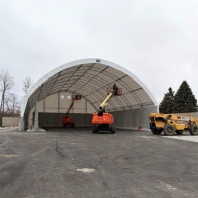 white arched struture with beams inside shows storage area with concrete walls and base in a concrete area outdoors