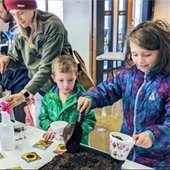 Child fills a decorated pot with soil