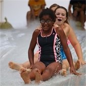 Friends slide with water on a plastic sheet