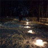 Child and adult follow ice luminaries on snow trail