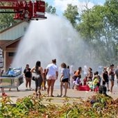 Families cool off with water spray from the fire truck